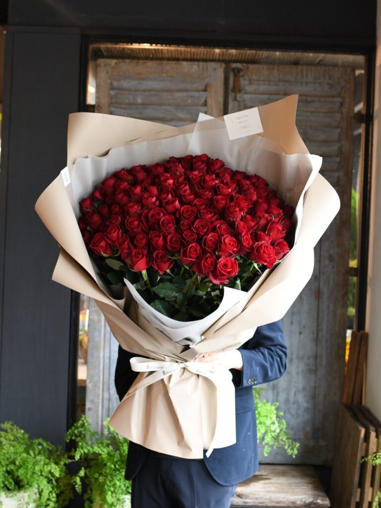 男性が抱える108本の赤い薔薇の花束のボリューム