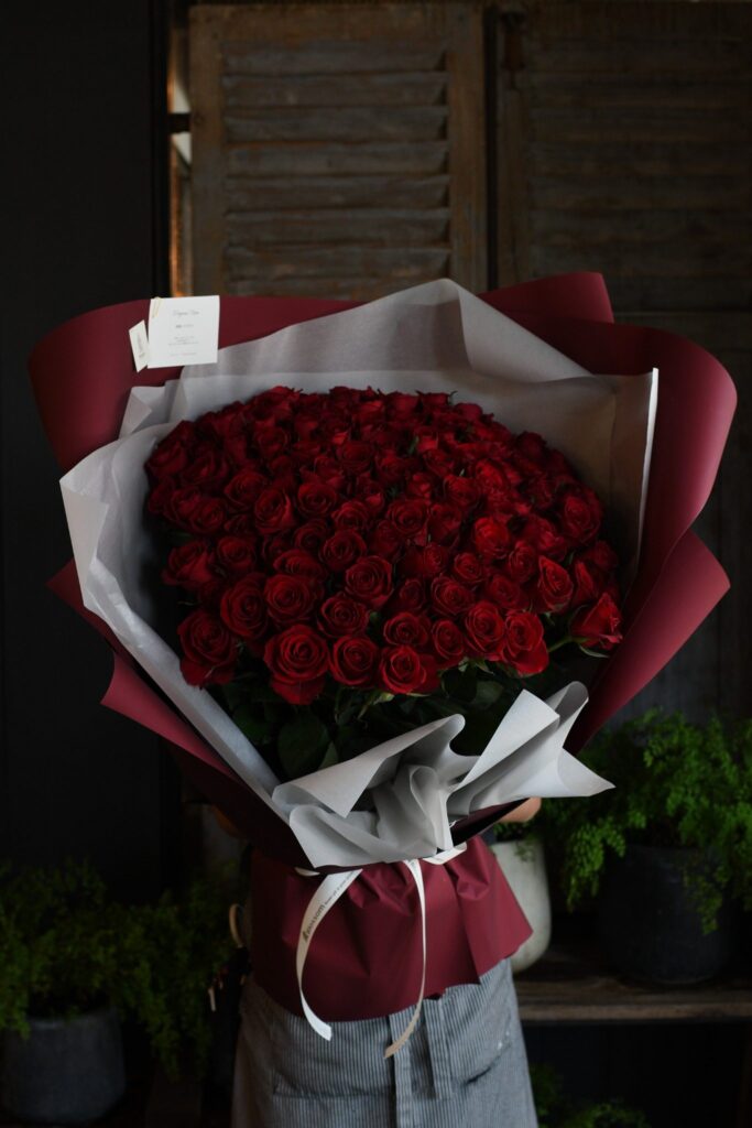 女性が抱える108本の赤い薔薇の花束の大きさ
