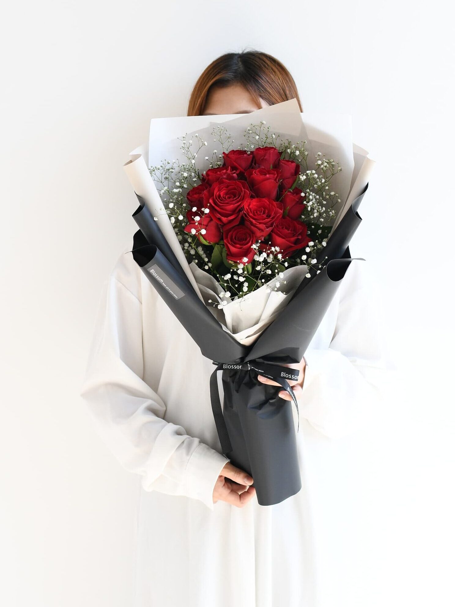 女性が持つ12本の赤い薔薇の花束のサイズ感