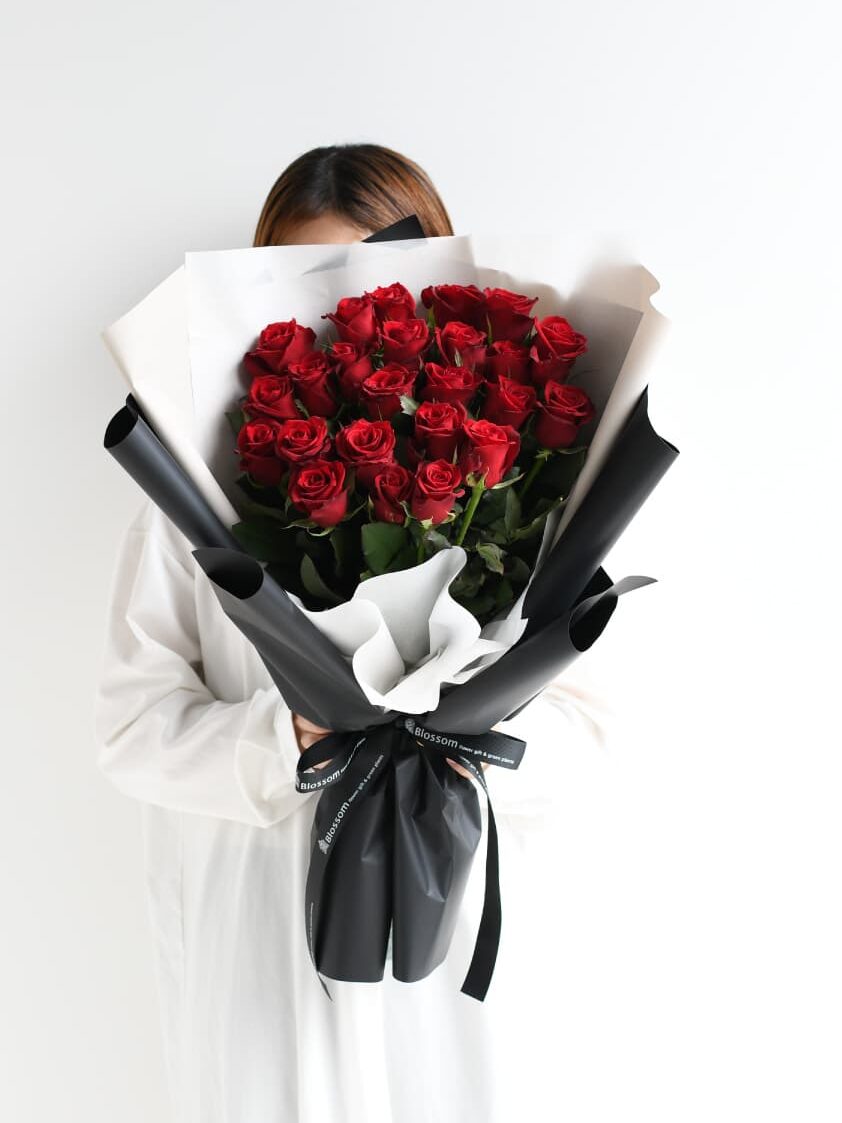 女性が持つ24本の赤い薔薇の花束のサイズ感