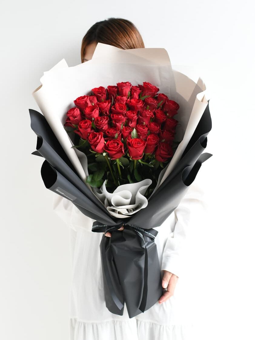 女性が持つ33本の赤い薔薇の花束のサイズ感