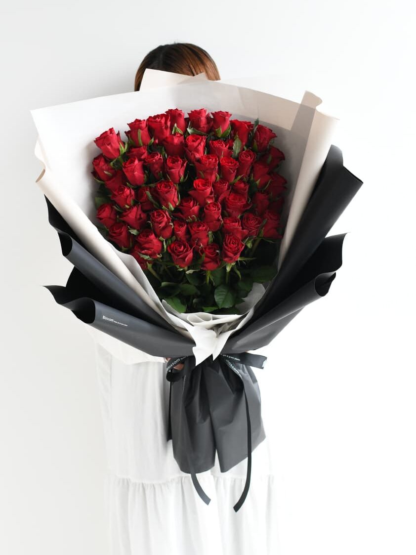 女性が持つ50本の赤い薔薇の花束のサイズ感