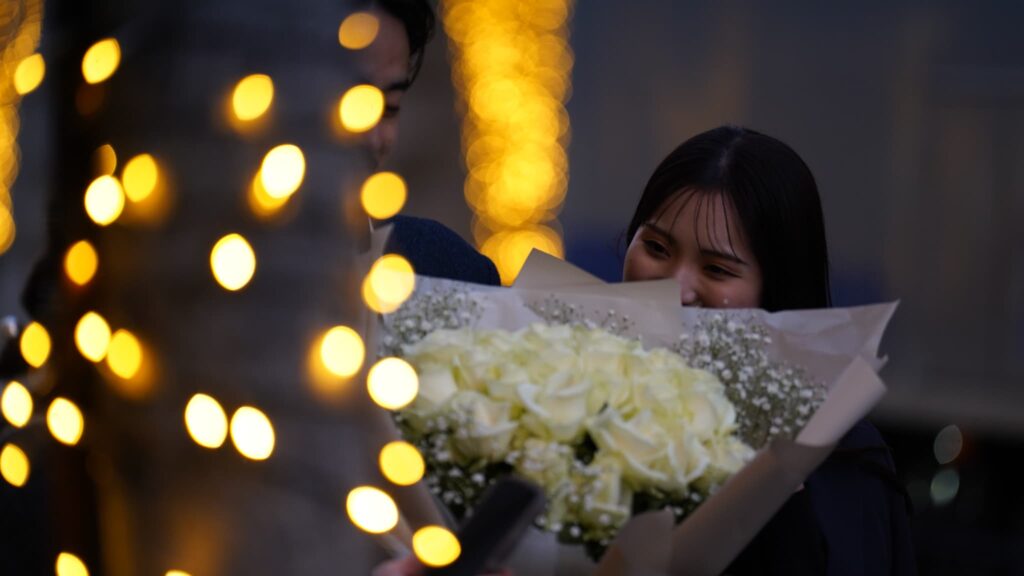 夜のプロポーズで薔薇の花束を受け取る女性